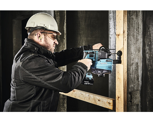 Bărbat cu cască de protecție și ochelari de protecție care găurește un perete cu un ciocan rotopercutor