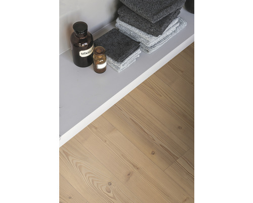 Raft cu prosoape gri și sticle de farmacie pe podea de lemn