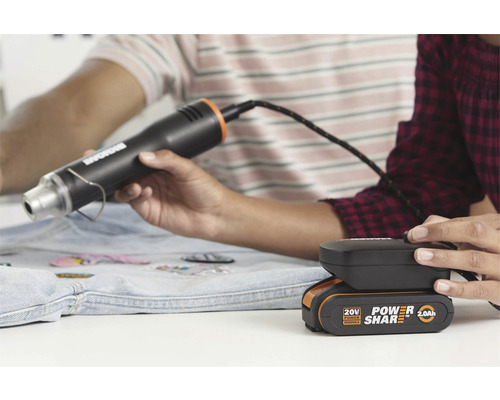 Pistol cu aer cald cu baterie utilizat pentru aplicarea plasturilor pe o jachetă de blugi