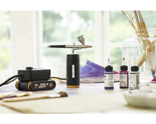 Sigla Worx pe setul de aerograf cu baterie și culori pe o masă