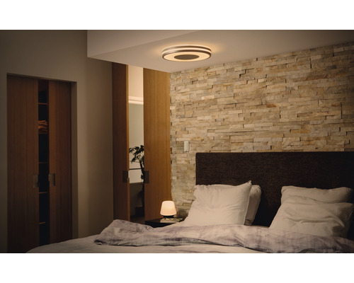 Dormitor cu pat matrimonial, perete de piatră și plafonieră rotundă
