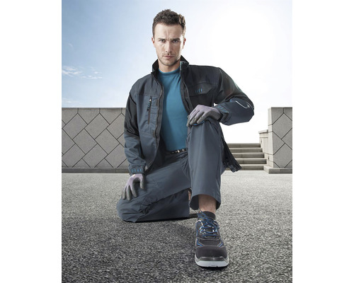 Bărbat îngenuncheat în haine de lucru cu jachetă, pantaloni, pantofi și mănuși