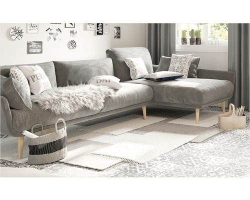 Cameră de zi cu canapea de colț gri, perne, covoare și decorațiuni.