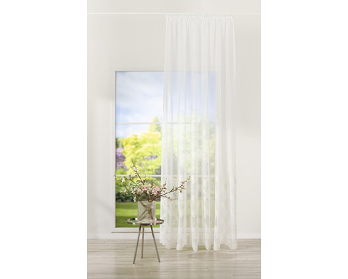 Cortină decorativă albă în fața unei ferestre cu flori de primăvară pe o măsuță laterală