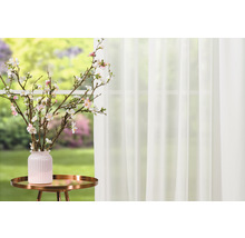 Natură statică decorativă cu draperie, măsuță laterală, vază și ramuri de flori de cireș în fața ferestrei