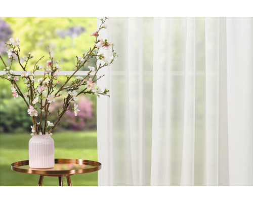 Natură statică decorativă cu draperie, măsuță laterală, vază și ramuri de flori de cireș în fața ferestrei