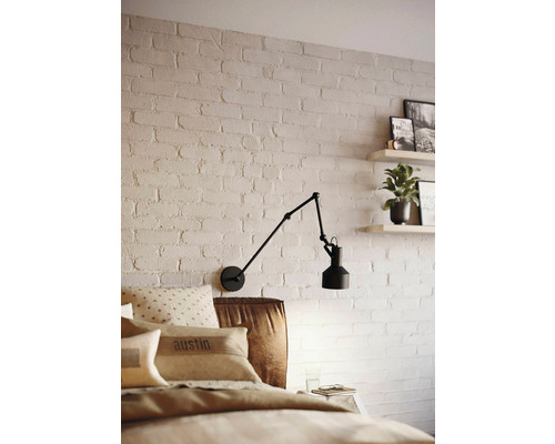 Dormitor cu perete de cărămidă, pat și lampă de perete reglabilă.