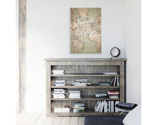 Tablou de perete cu hartă a lumii și citatul: A călători este un semn de curaj deasupra unei biblioteci