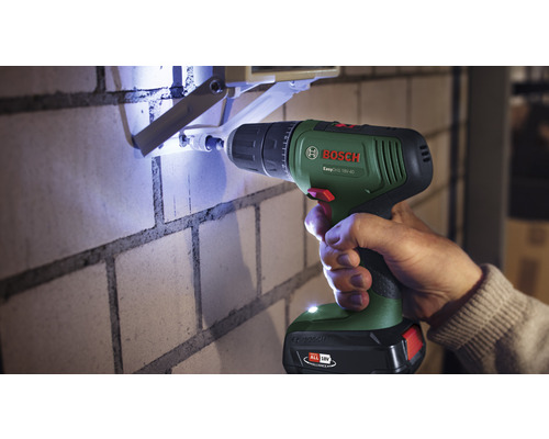 Mașină de găurit care găurește un perete de cărămidă