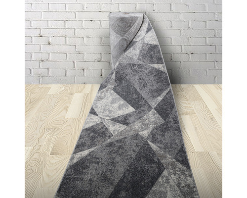 Covor gri cu model geometric, rulat în fața unui perete de cărămidă