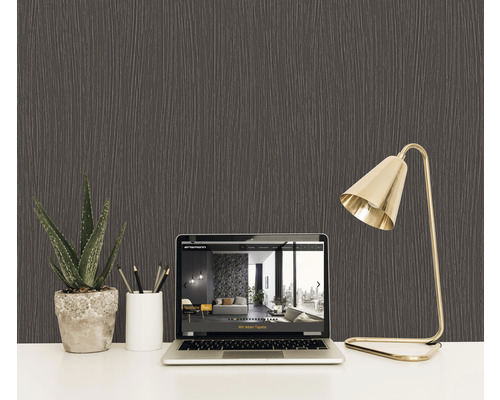 Prim-plan cu un tapet texturat închis la culoare pe fundalul unui birou cu laptop, plantă și lampă