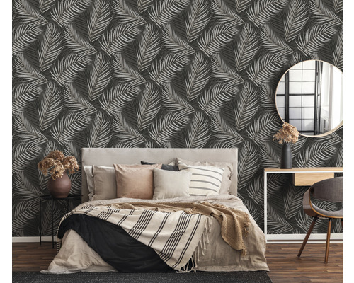 Dormitor cu pat în fața unui perete cu tapet cu model de frunze.