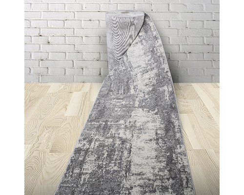 Covor gri pe rolă în fața unui zid de cărămidă