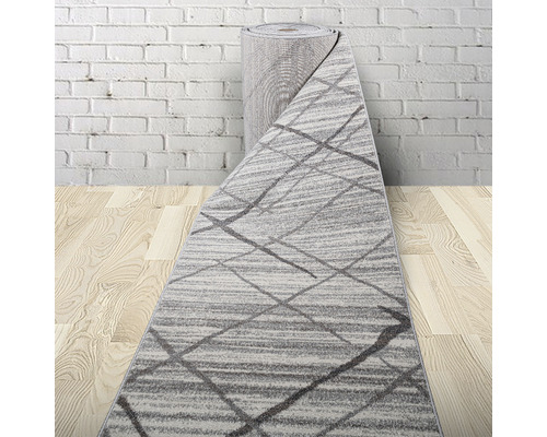 Covor rulat cu model geometric pe podea de lemn în fața unui perete de cărămidă