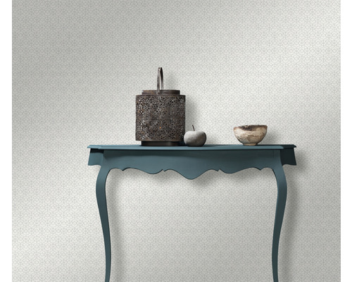 Scenă decorativă cu masă, felinar, bol și măr în fața unui tapet cu model