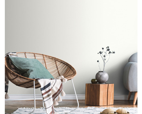 Cameră de zi decorativă cu fotoliu din ratan, masă din lemn și pereți luminoși