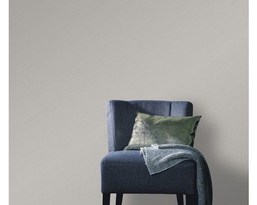 Scenă cu un fotoliu albastru-gri cu pernă și pătură în fața unui tapet gri, creând o ambianță luminoasă și organizată