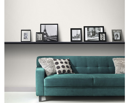 Living modern cu canapea turcoaz, perne și o serie de rame foto pe un raft