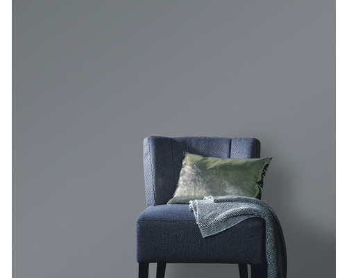 Tapetă uni în spatele unui fotoliu cu pernă și pătură