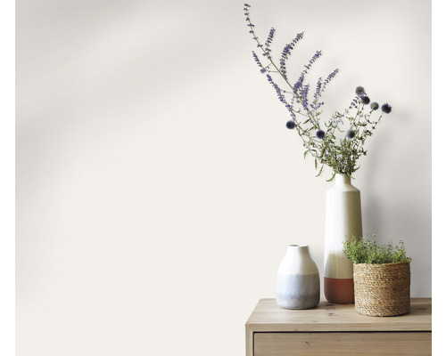 Vaze decorative cu flori pe o masă de lemn în fața unui perete