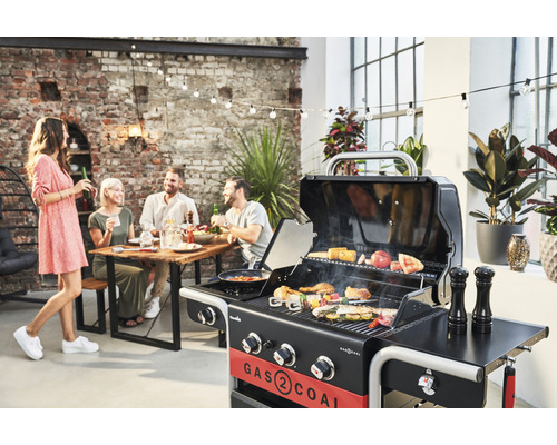 Scenă în aer liber cu grătar pe cărbune, masă și oameni