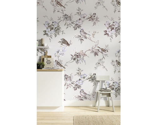 Cameră cu tapet cu model de păsări și flori, un dulap alb și un scaun.