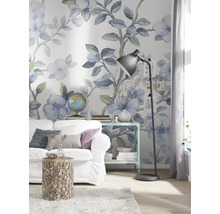 Cameră de zi decorată cu canapea, măsuță laterală și lampă de podea în fața unui tapet floral
