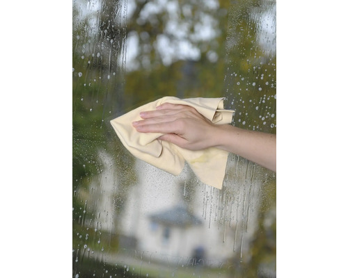 Mână șterge o suprafață de sticlă cu o cârpă