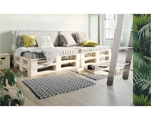 Cameră de zi cu canapea din paleți, perne și covor pe podea de lemn