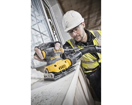 Artizan șlefuiește rama ferestrei cu o șlefuitoare orbitală DeWalt