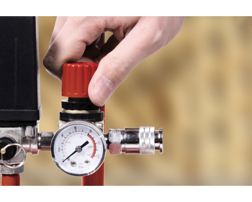Mână care operează regulatorul de presiune pe un compresor