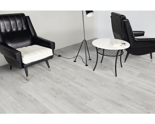 Cameră de zi cu podea de vinil deschisă la culoare, fotolii, lampă de podea și măsuță laterală