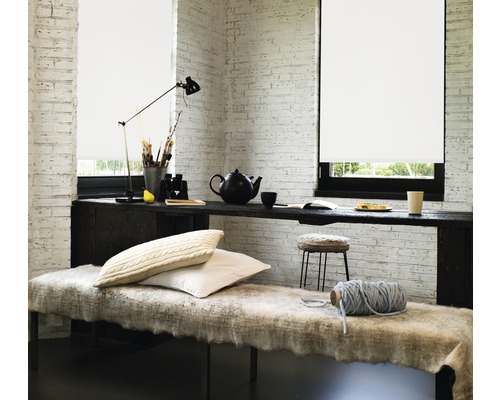 Cameră luminoasă cu jaluzele la ferestre, o masă lungă ca spațiu de lucru și o zonă de relaxare confortabilă