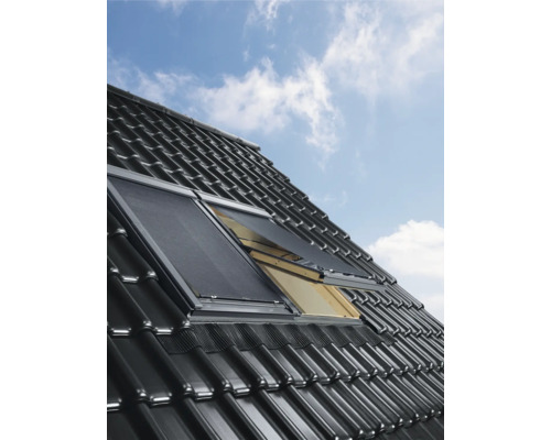 Fereastră de mansardă cu jaluzea pe un acoperiș de țiglă