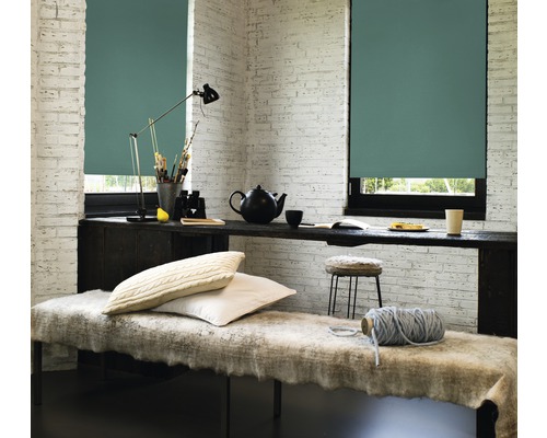 Cameră luminoasă cu două ferestre cu jaluzele, o bancă și un birou cu obiecte decorative