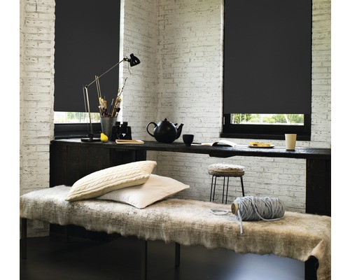 Cameră cu jaluzele negre, masă și banchetă în fața unui zid de cărămidă