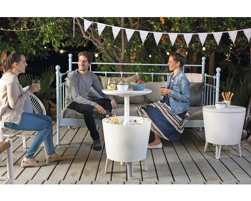 Trei persoane stau pe o terasă cu cutii frigorifice și măsuțe laterale