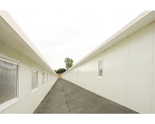 Coridor lung între două rânduri de containere de birou cu ferestre