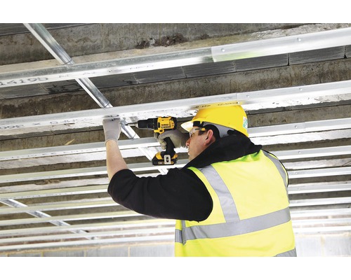 Un muncitor în construcții fixează o structură de tavan cu o șurubelniță cu acumulator.