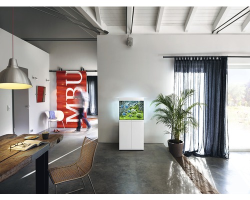 Living cu acvariu pe dulap inferior, masă și scaune.