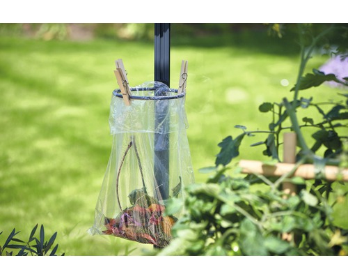 Coș de gunoi cu frunze, atașat de un stâlp, în grădină