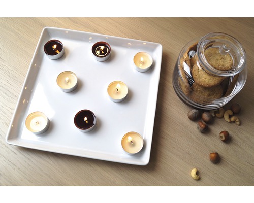 Lumânări decorative pe o farfurie cu biscuiți într-un borcan și nuci