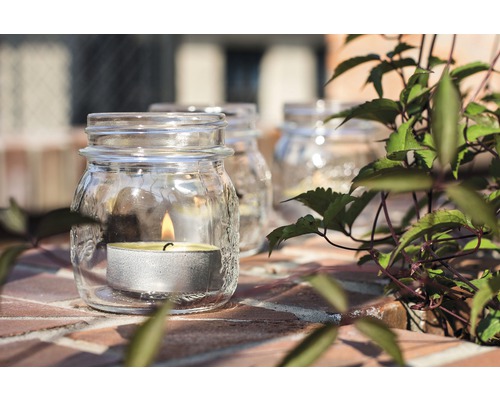 Suport de lumânare din sticlă cu lumânare tip pastilă pe suprafață de cărămidă