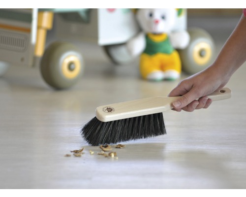 Mătură de mână cu mâner de lemn și peri negri mătură firimiturile de pe podea.