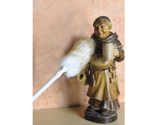 Pămătuful de praf curăță o figurină de călugăr din lemn