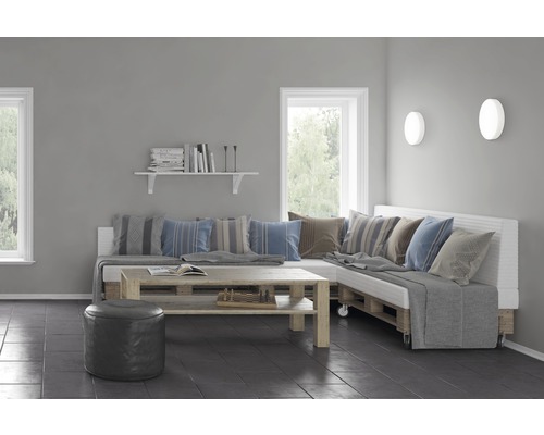 Cameră de zi luminoasă cu canapea din paleți, masă din lemn, fereastră și lămpi de perete