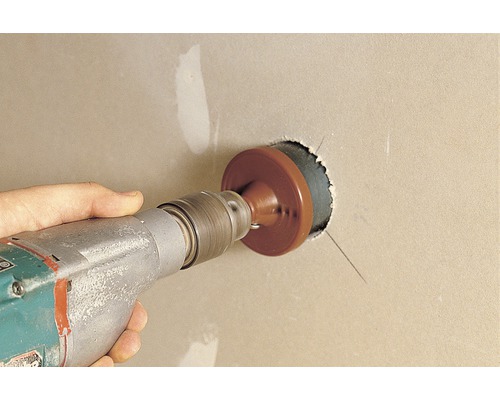 O mașină de găurit cu ferăstrău circular găurește un perete din gips-carton.