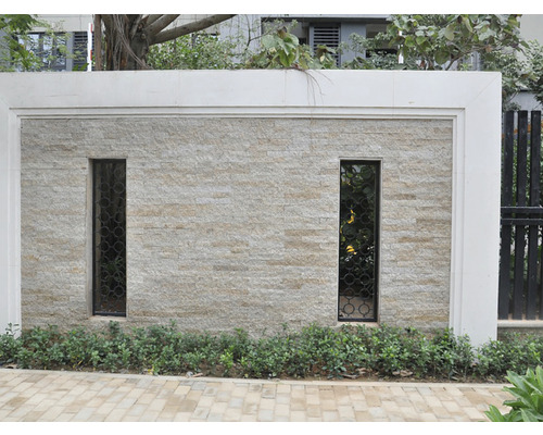 Un zid cu două ferestre înguste și furnir de piatră