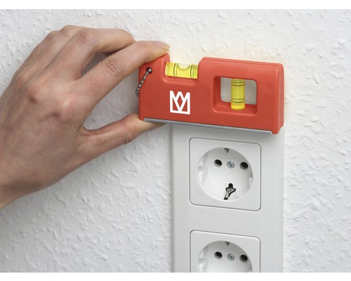 O mână ține o nivela pe o priză electrică pentru a verifica alinierea.