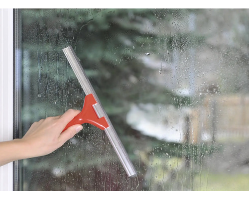 Mână care folosește o racletă pe o suprafață de fereastră